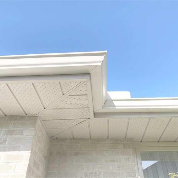 corner sections of seamless eavestroughs framing soffit in front of blue sky