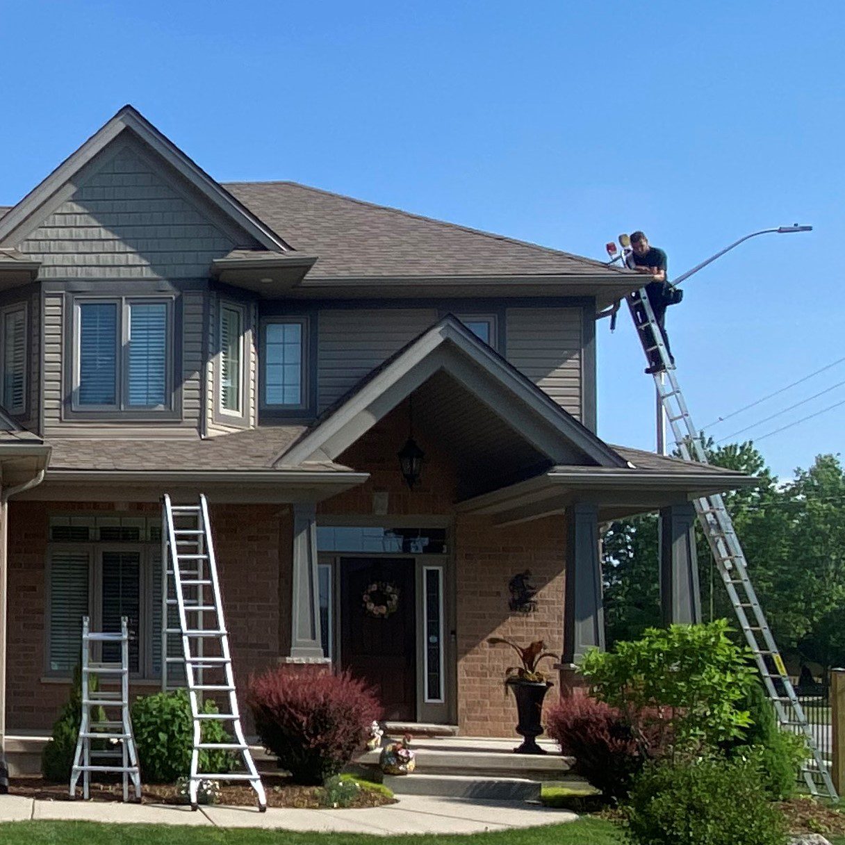 Eavestrough Maintenance Tips - man on ladder inspecting eavestrough on second story of home